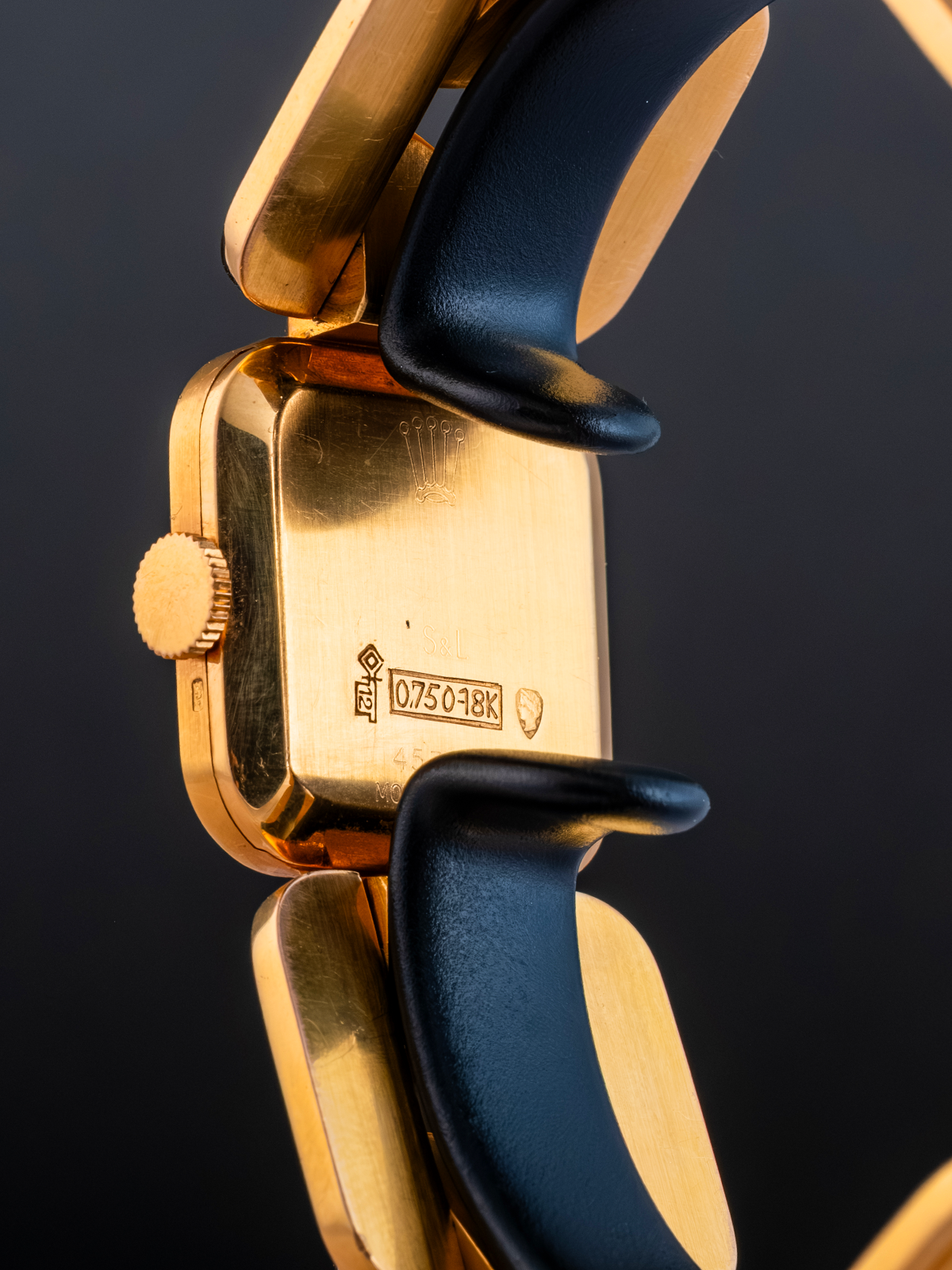 Close-up of a gold watch with black strap on a dark background