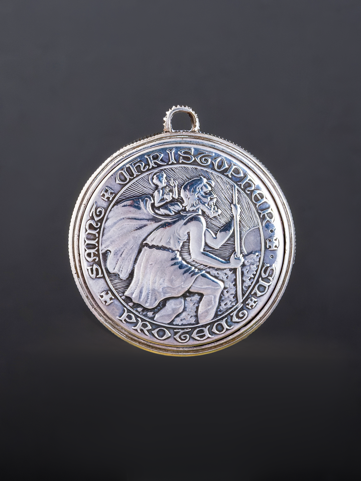 Silver pendant with intricate design on a dark background