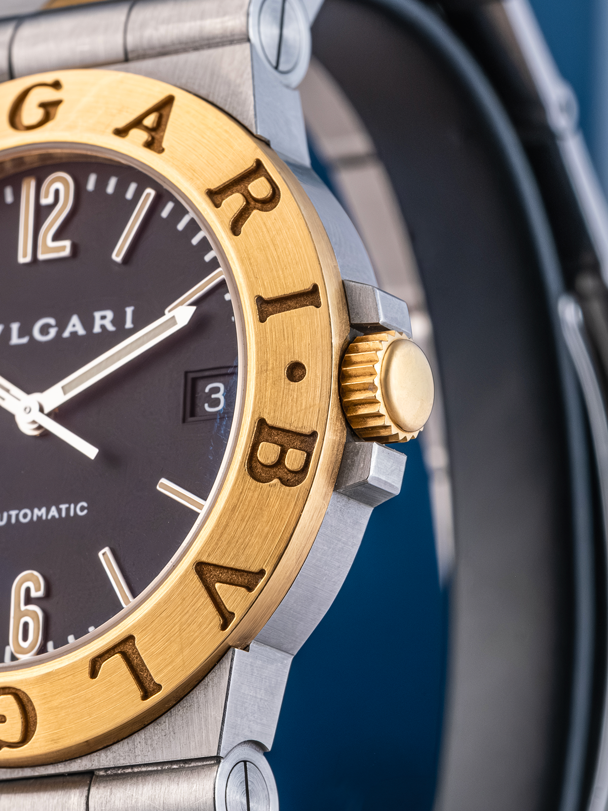 Bulgari watch with gold bezel and black dial on a blue background