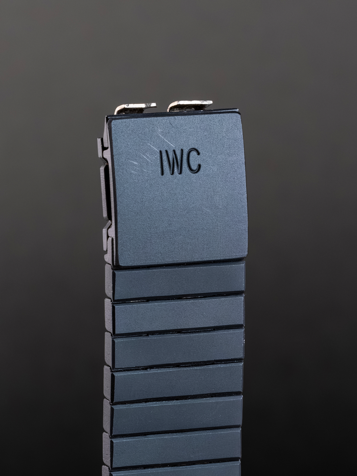 Blue watch strap with 'IWC' branding on a dark gray background