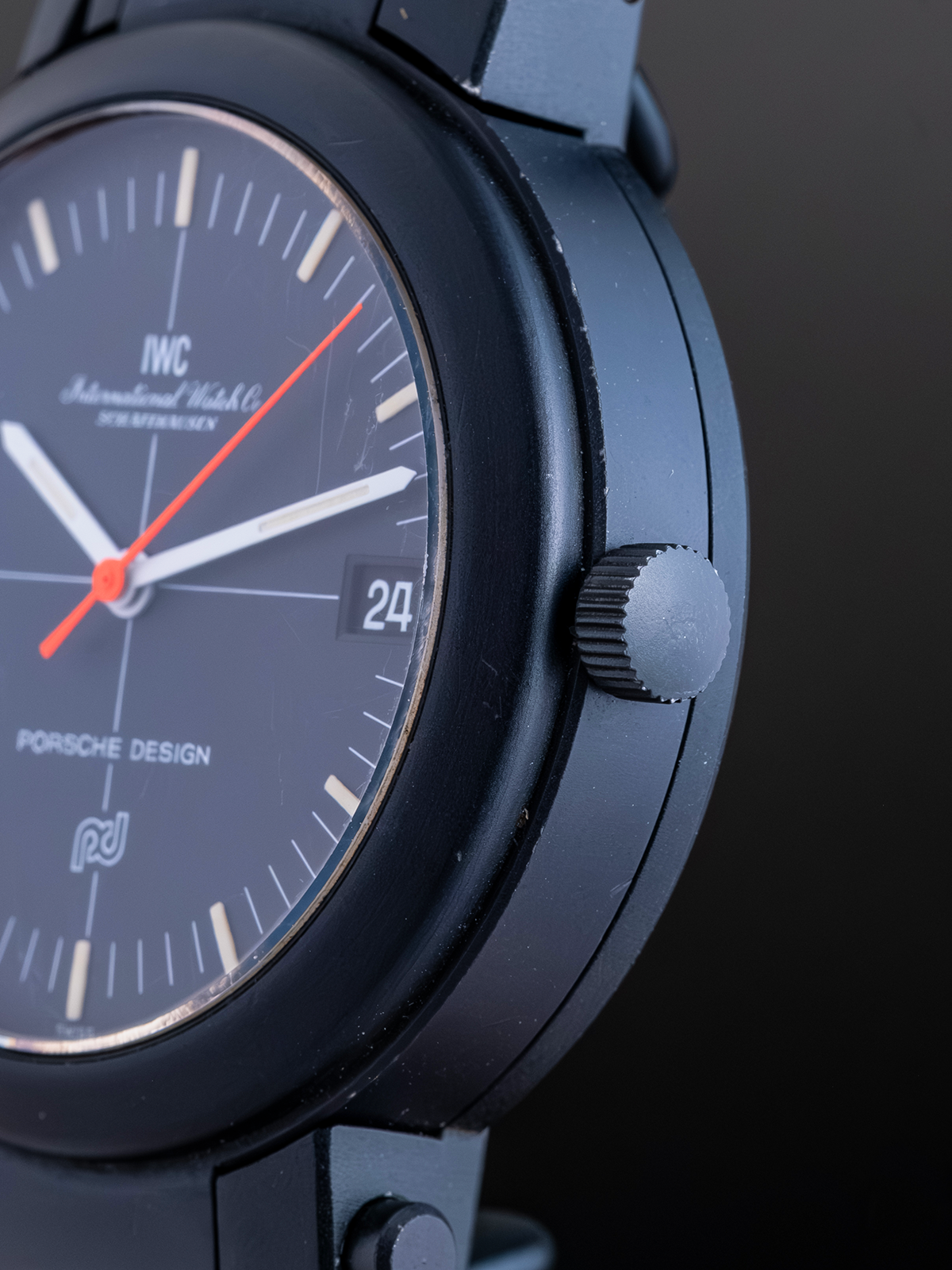 Close-up of a Porsche Design watch with a dark face and blue case.