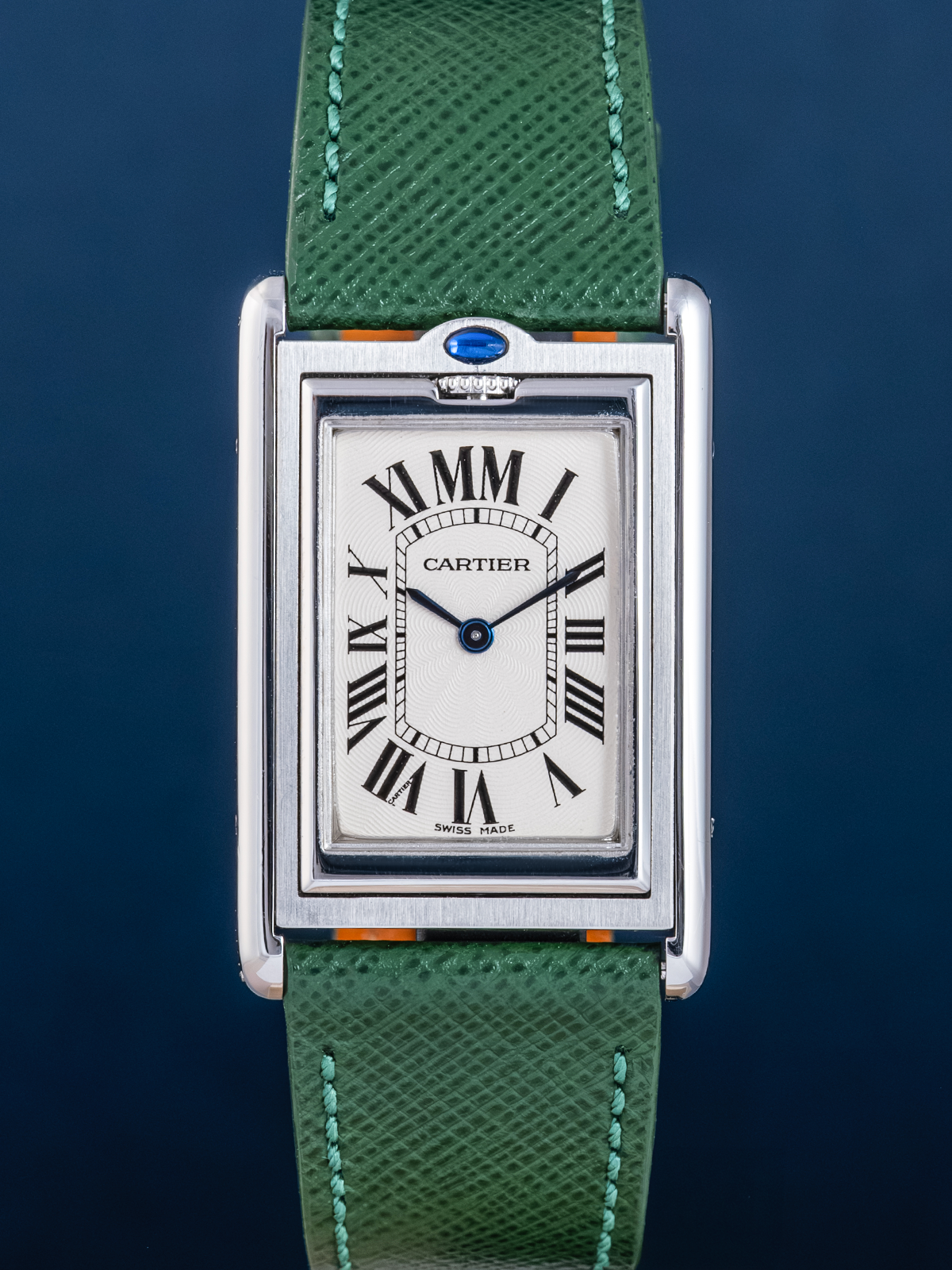 Cartier watch with green strap on a dark blue background
