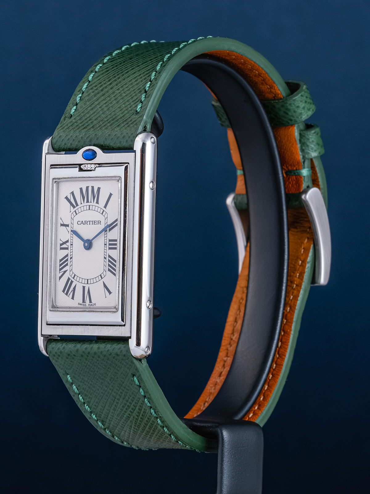 Cartier watch with green strap on a dark blue background