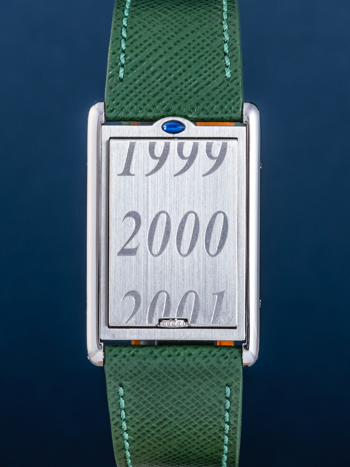 Watch with a green strap and silver case displaying years 1999, 2000, and 2001 on a dark blue background