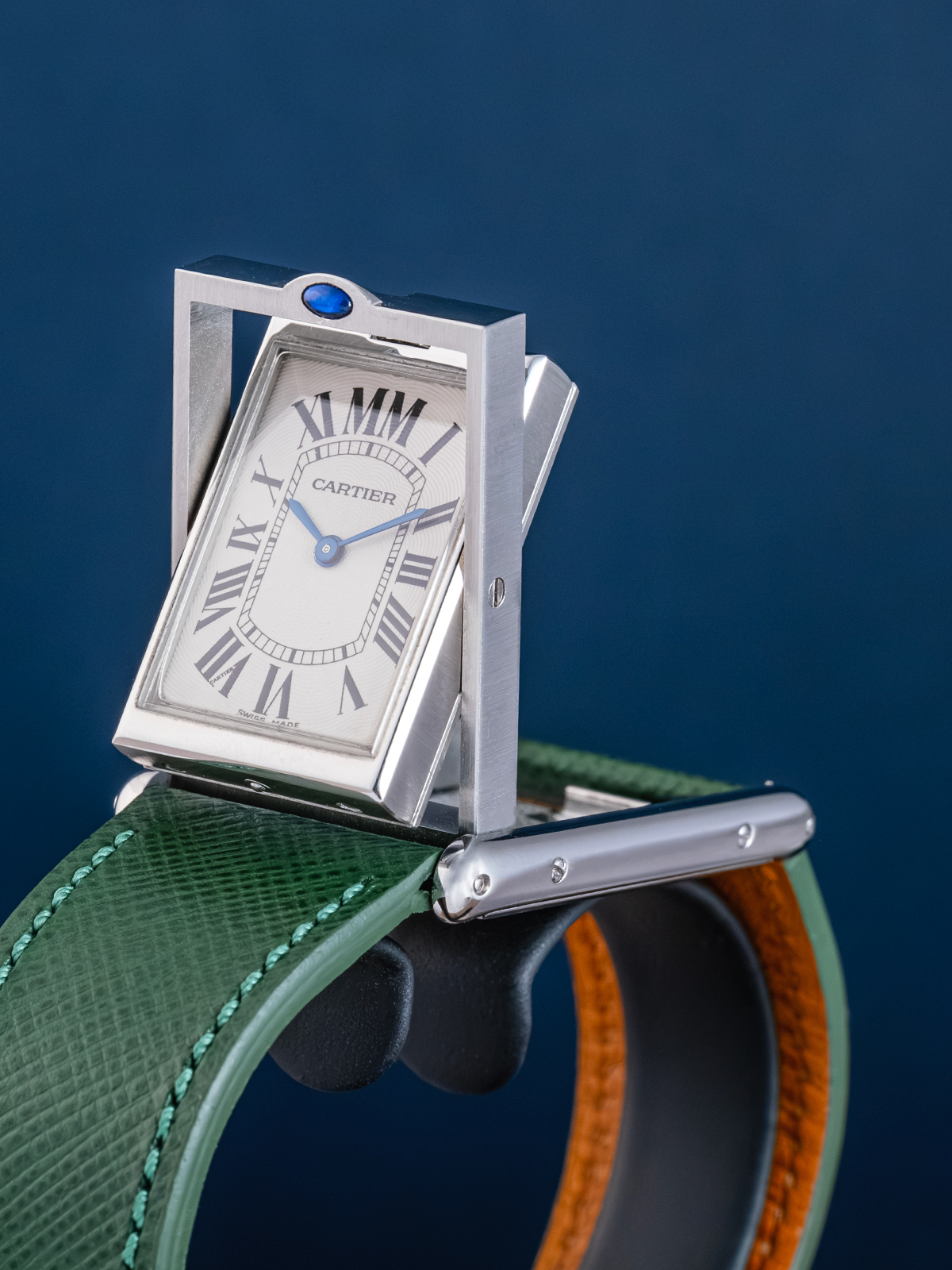 Cartier watch with a green strap on a blue background