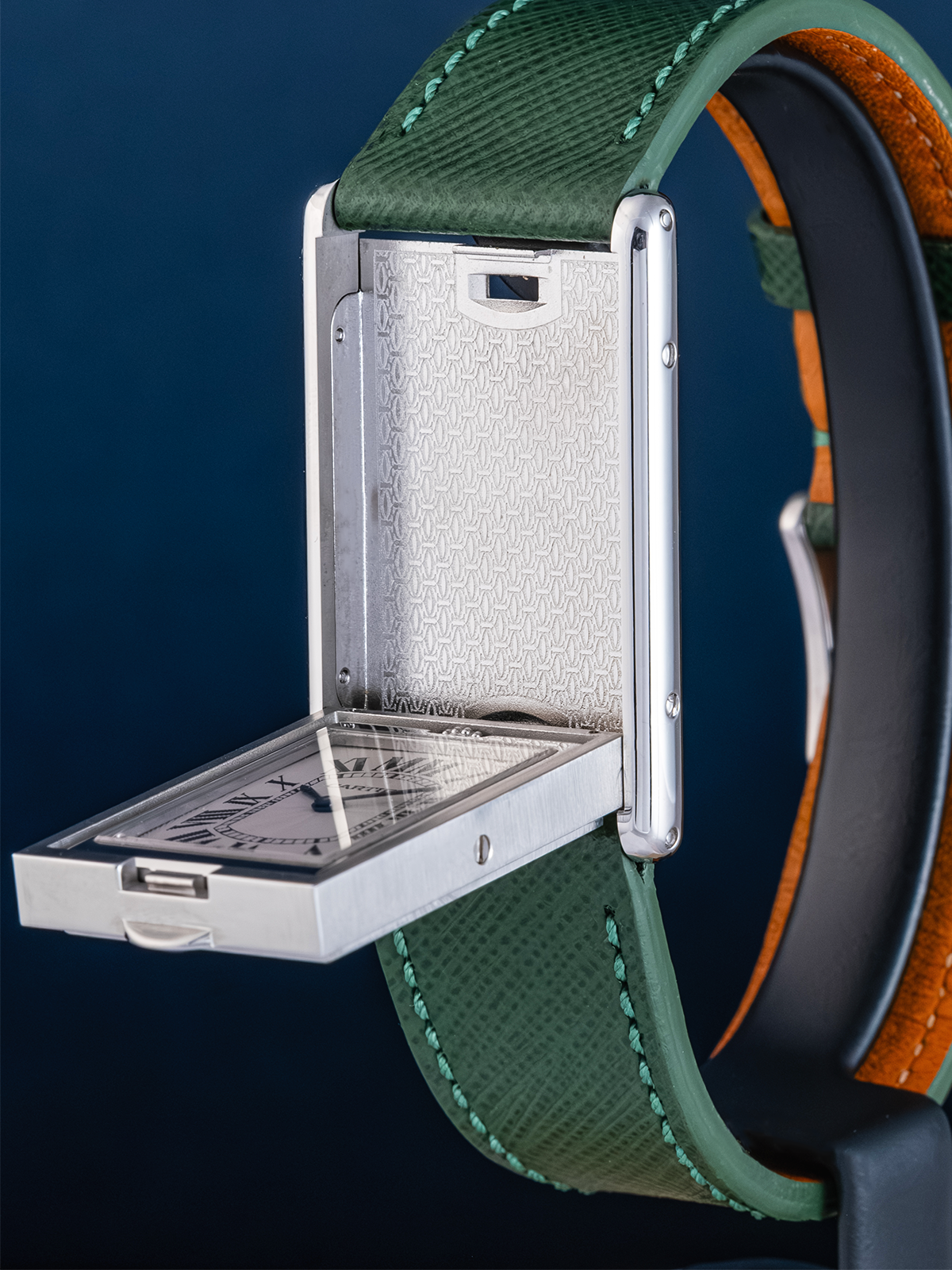 Close-up of a watch with a green strap and silver case on a dark blue background