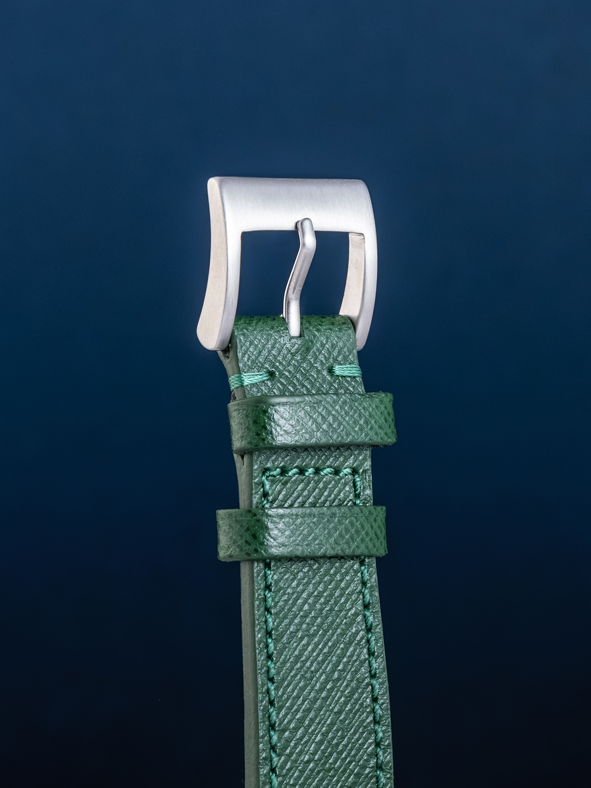 Green watch strap with silver buckle on a dark blue background