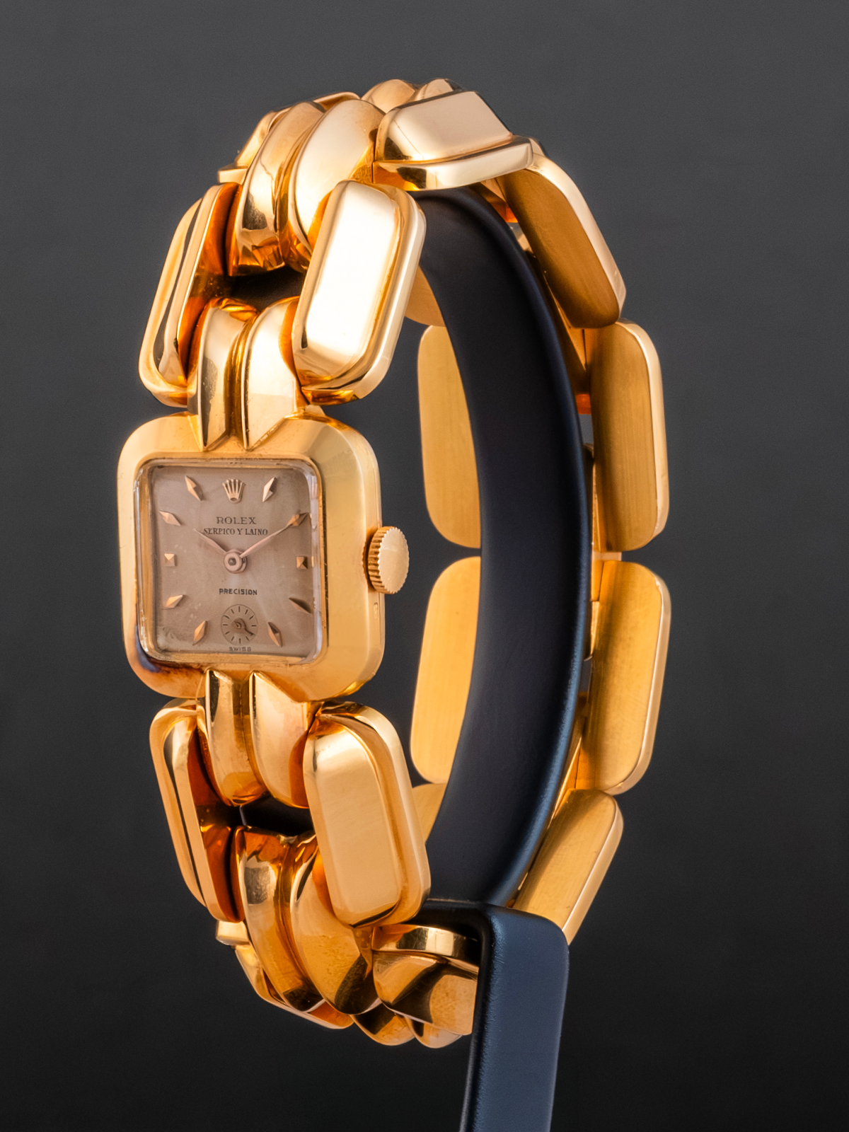 Gold watch with a black strap on a dark background