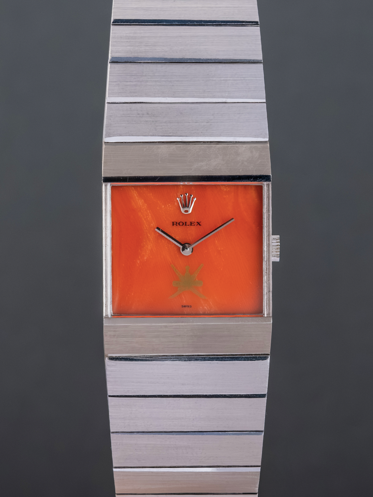 Rolex watch with orange face and silver band on a dark background