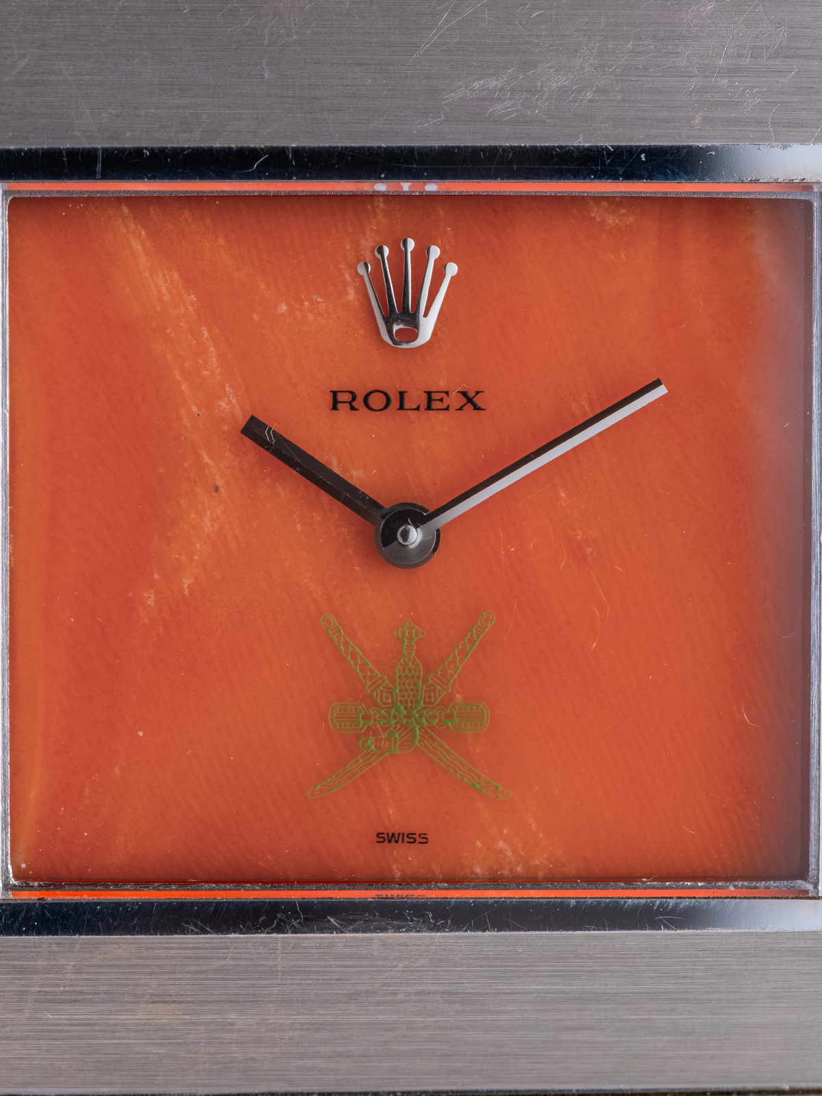 Rolex clock with orange face and gold emblem on a dark background