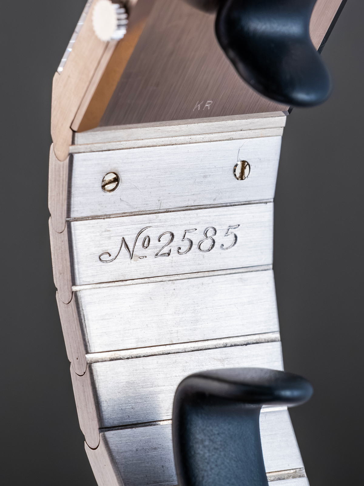 Close-up of a watch with 'No. 2585' engraving on a dark background