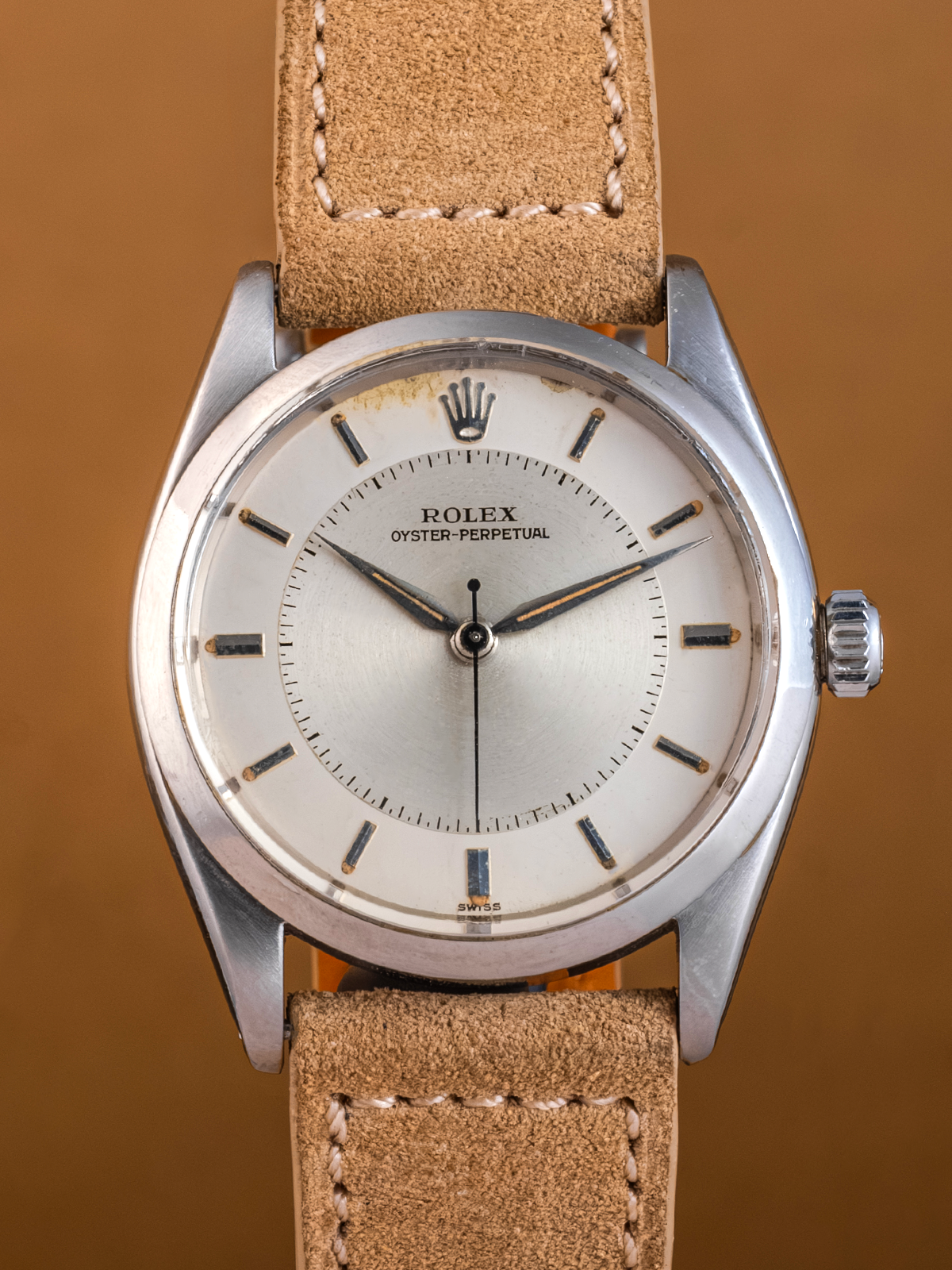 Vintage Rolex watch with brown leather strap on a brown background
