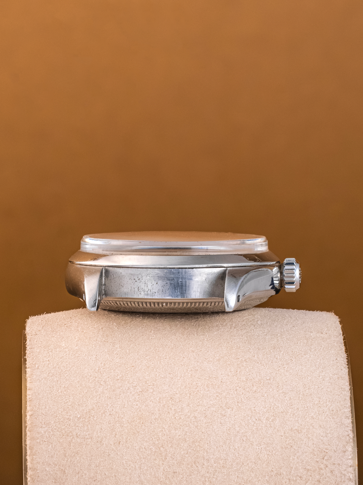 Silver watch on a beige cushion against a brown background