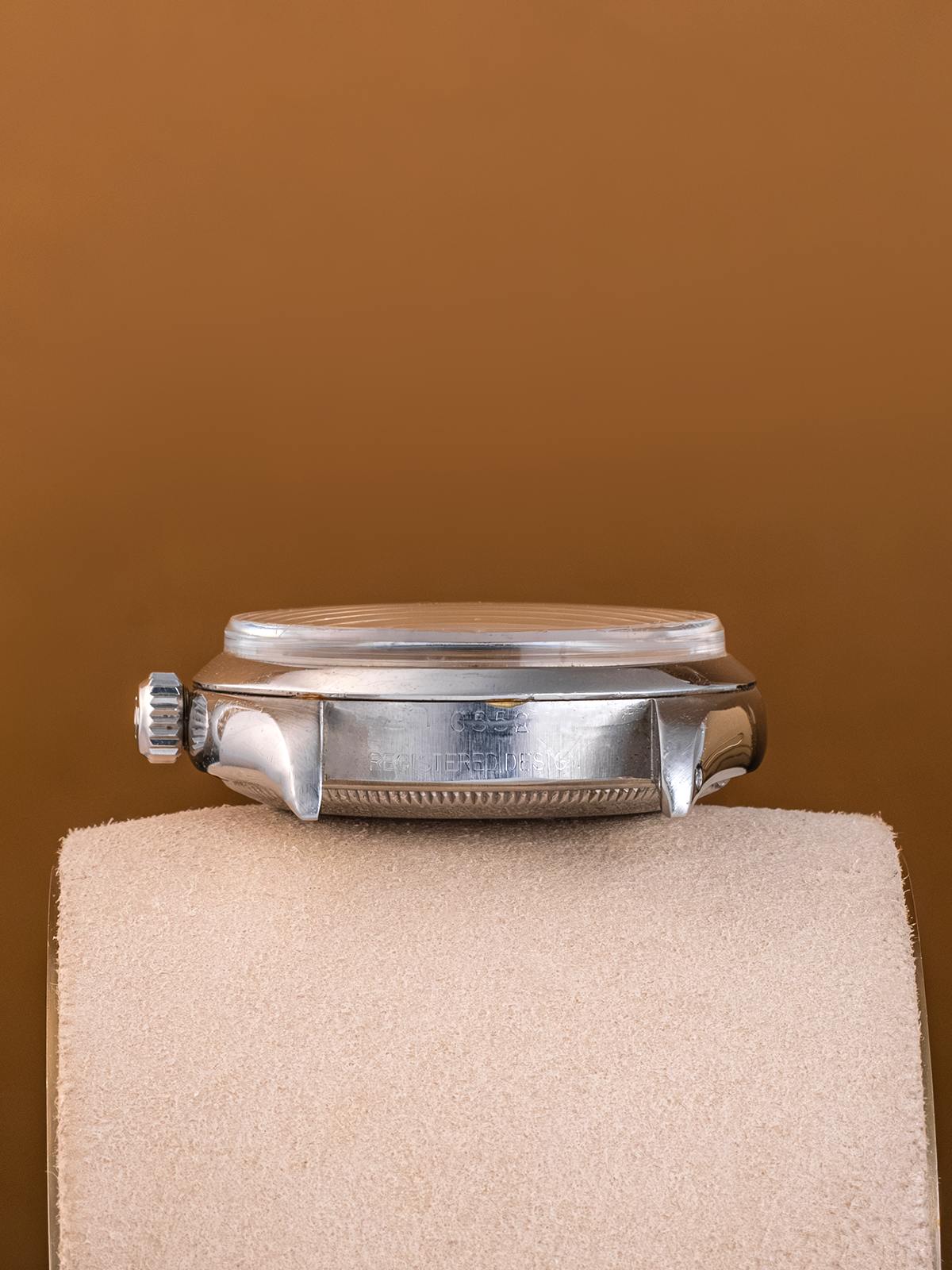 Silver watch on a beige cushion against a brown background