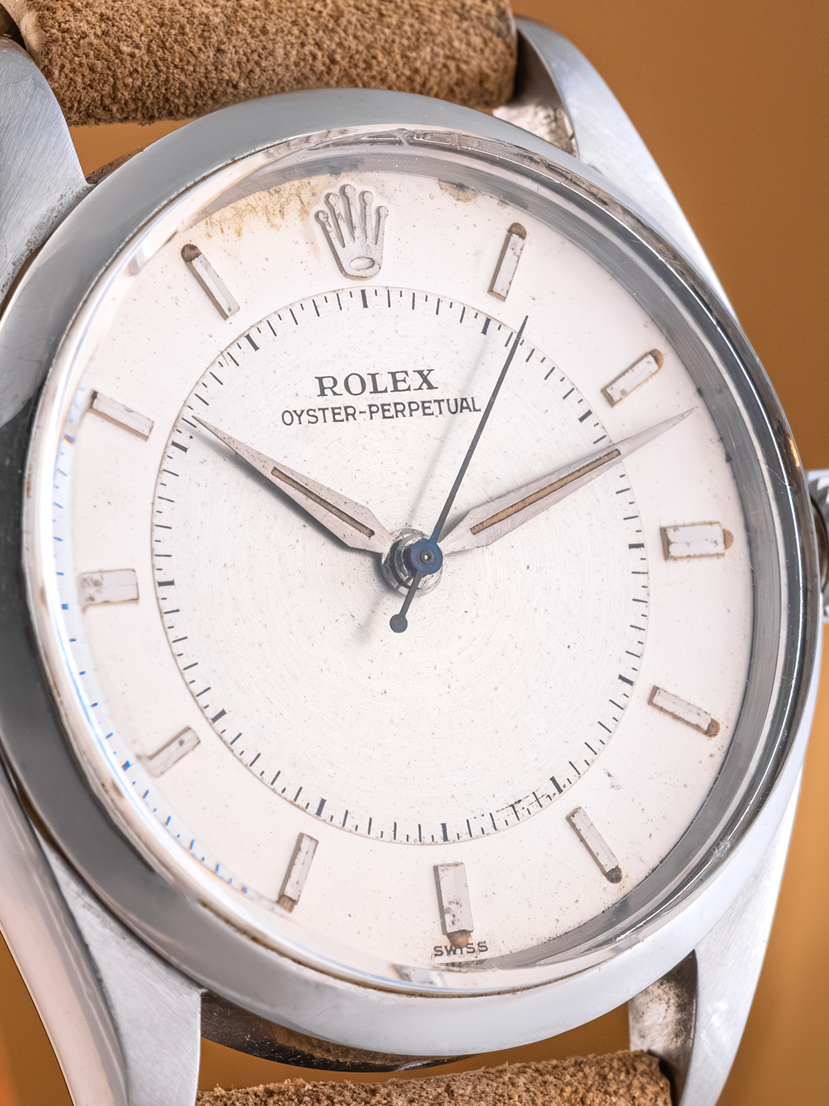 Close-up of a Rolex watch with a white face and brown leather strap.