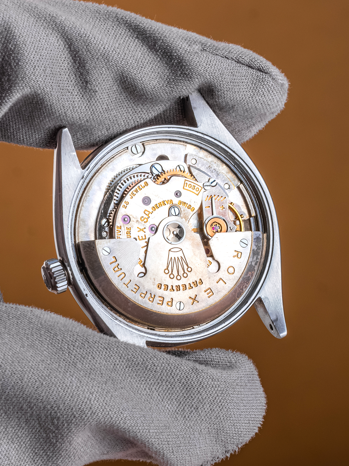 Close-up of a mechanical watch with visible brand name on a brown background