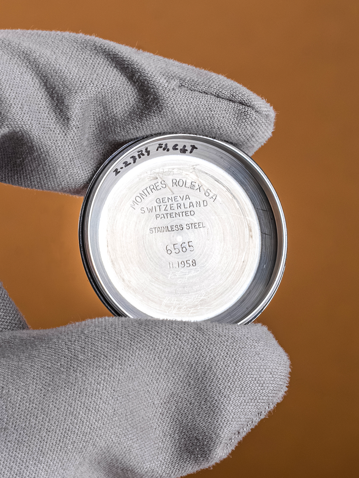 Close-up of a Rolex watch caseback with branding on a brown background