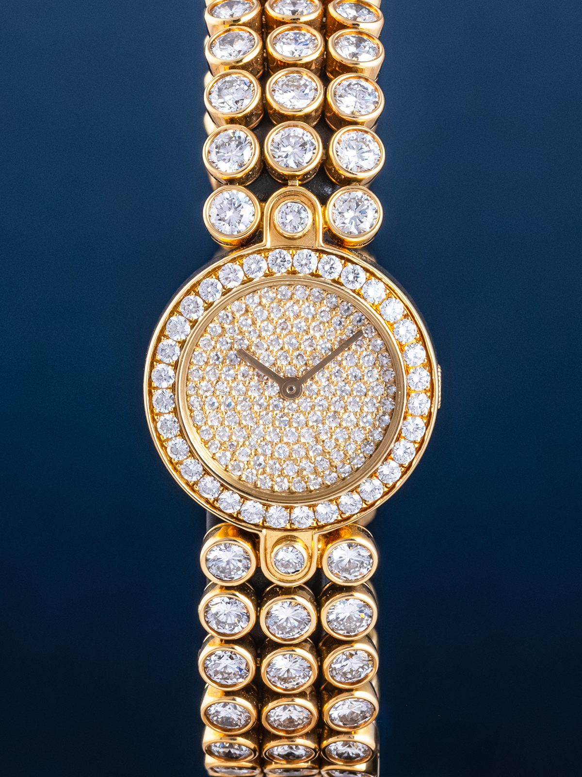 Gold watch with diamond-studded bracelet on a dark background