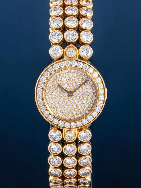 Gold watch with diamond-studded bracelet on a dark background