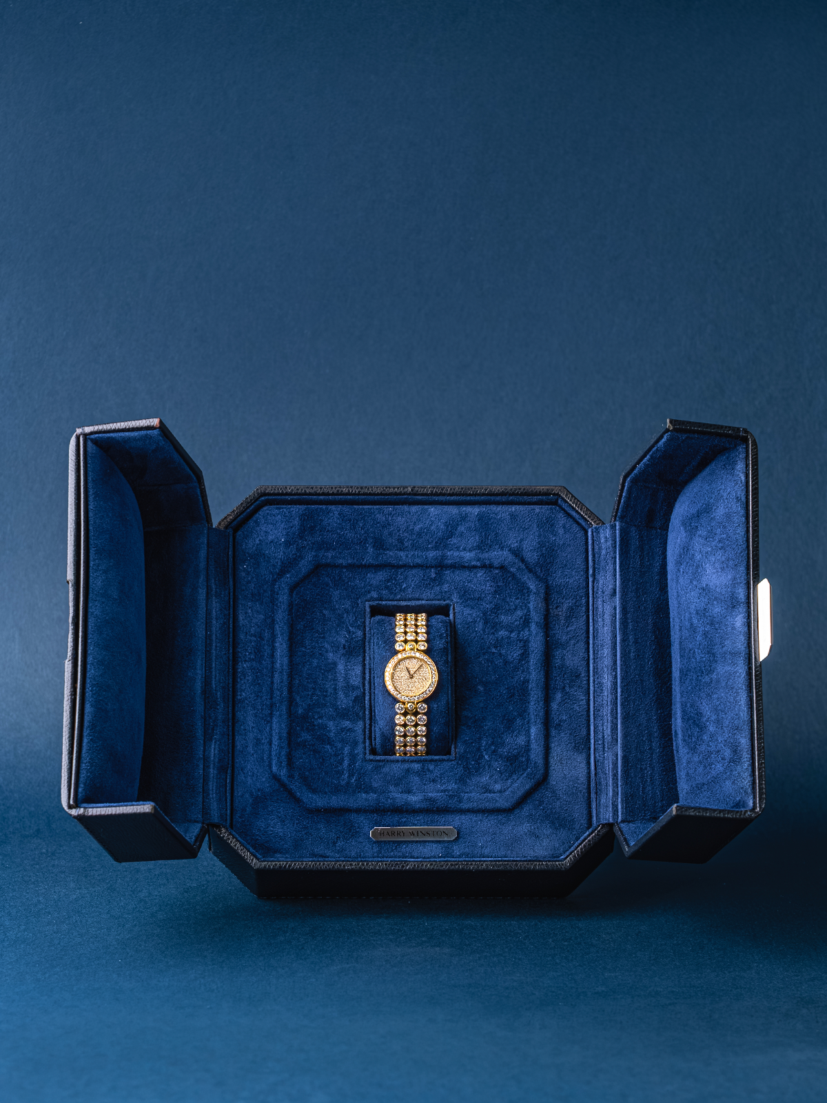 Gold watch in a blue velvet box on a matching blue background