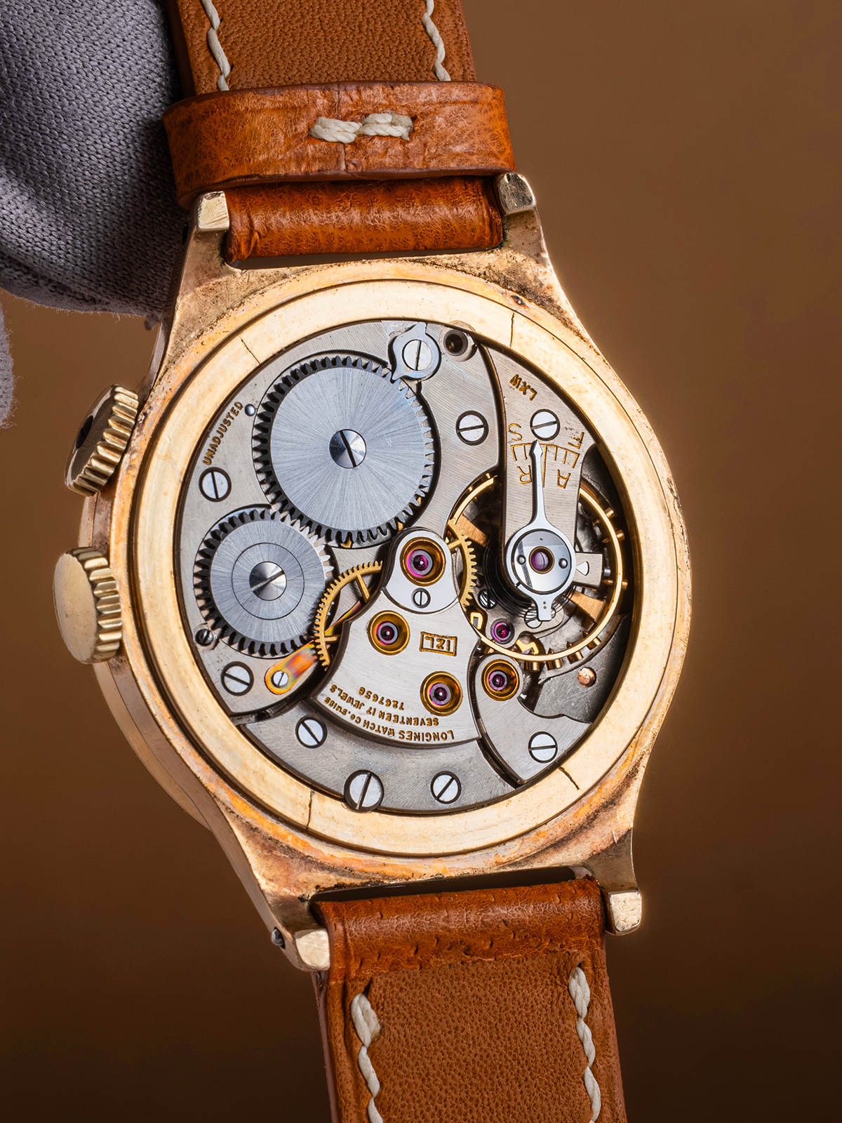 Close-up of a mechanical watch with a brown leather strap on a blurred background