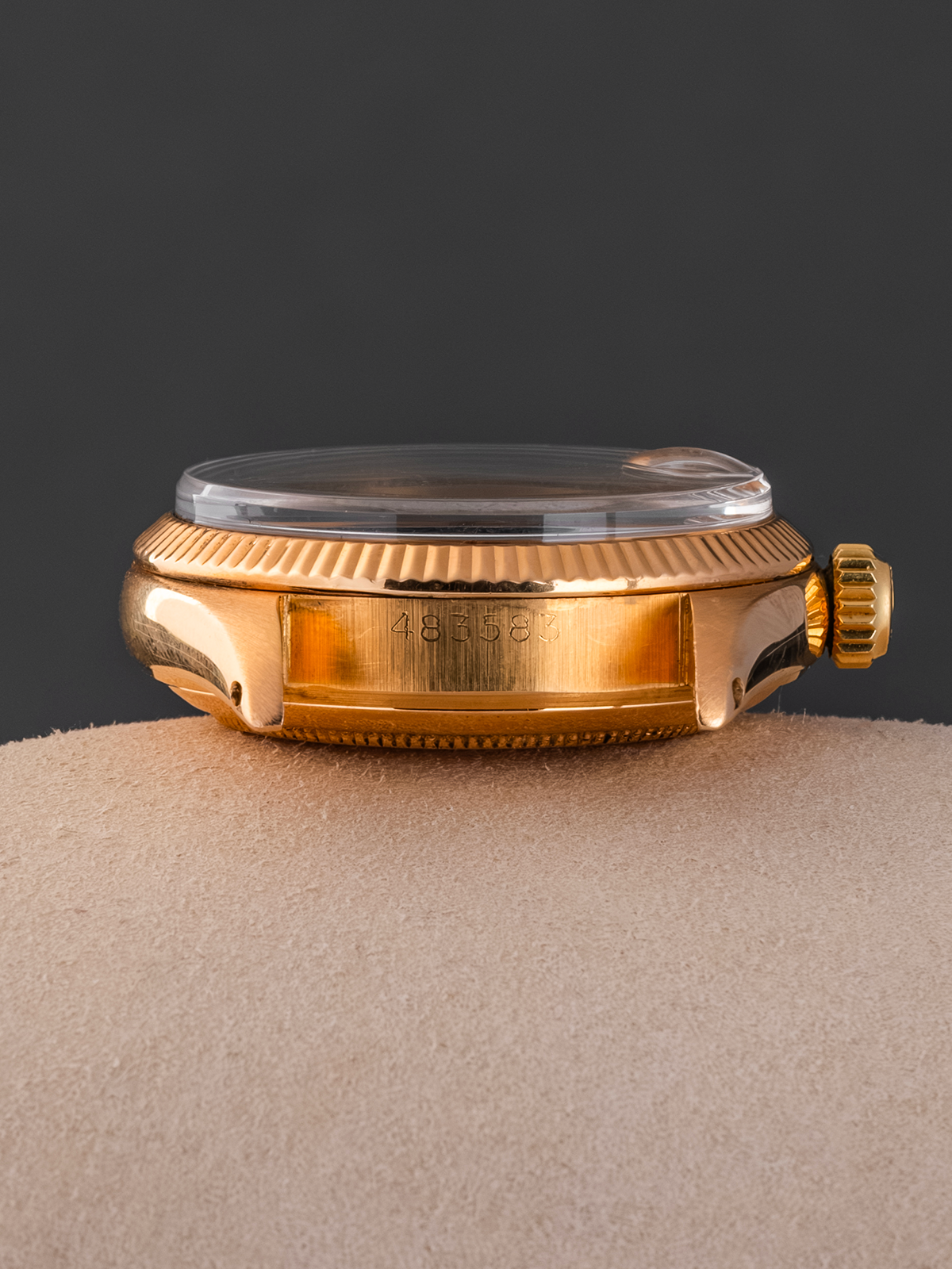 Gold watch case on a textured surface with a dark background