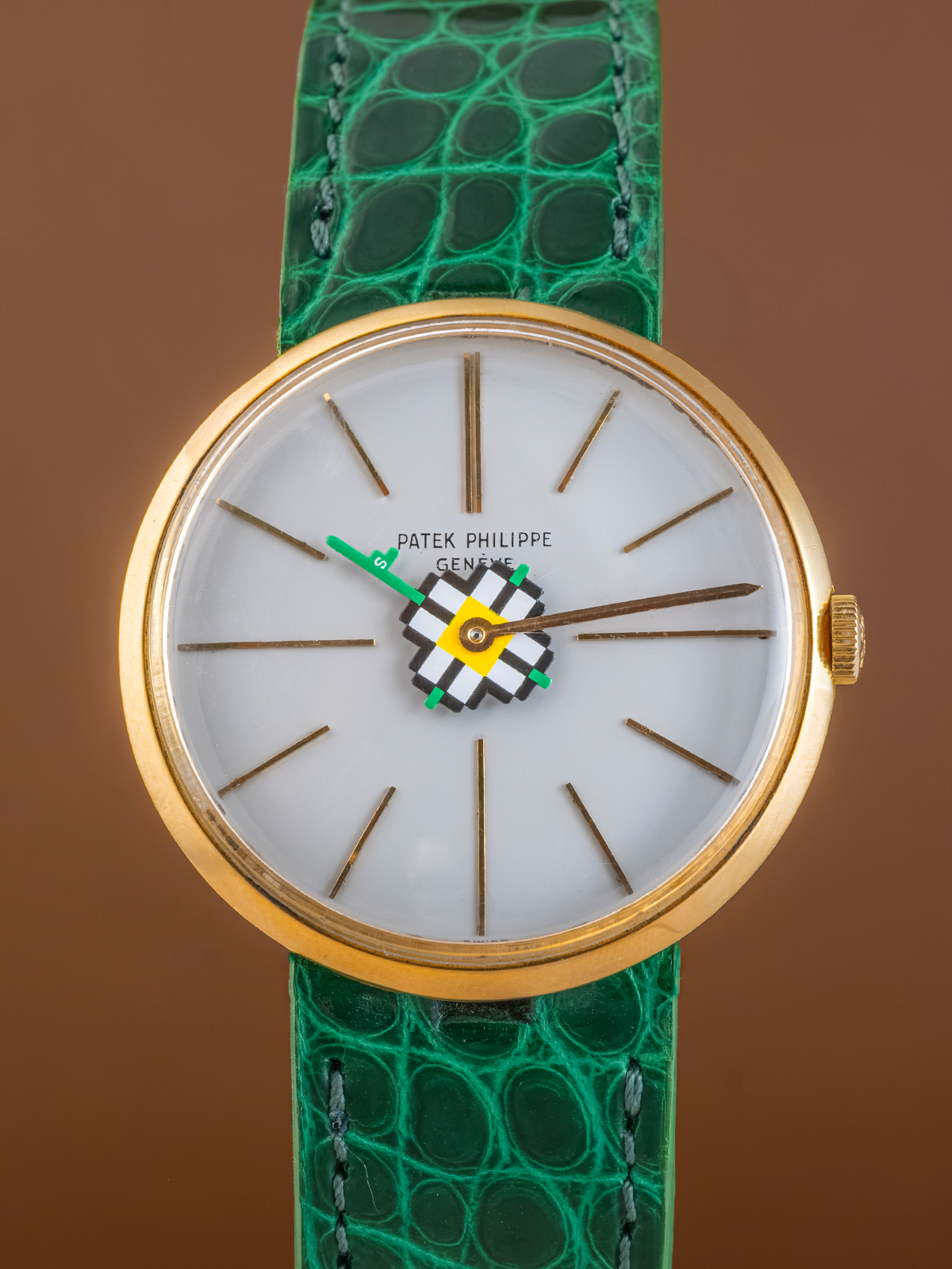 Watch with green strap and gold case on a brown background