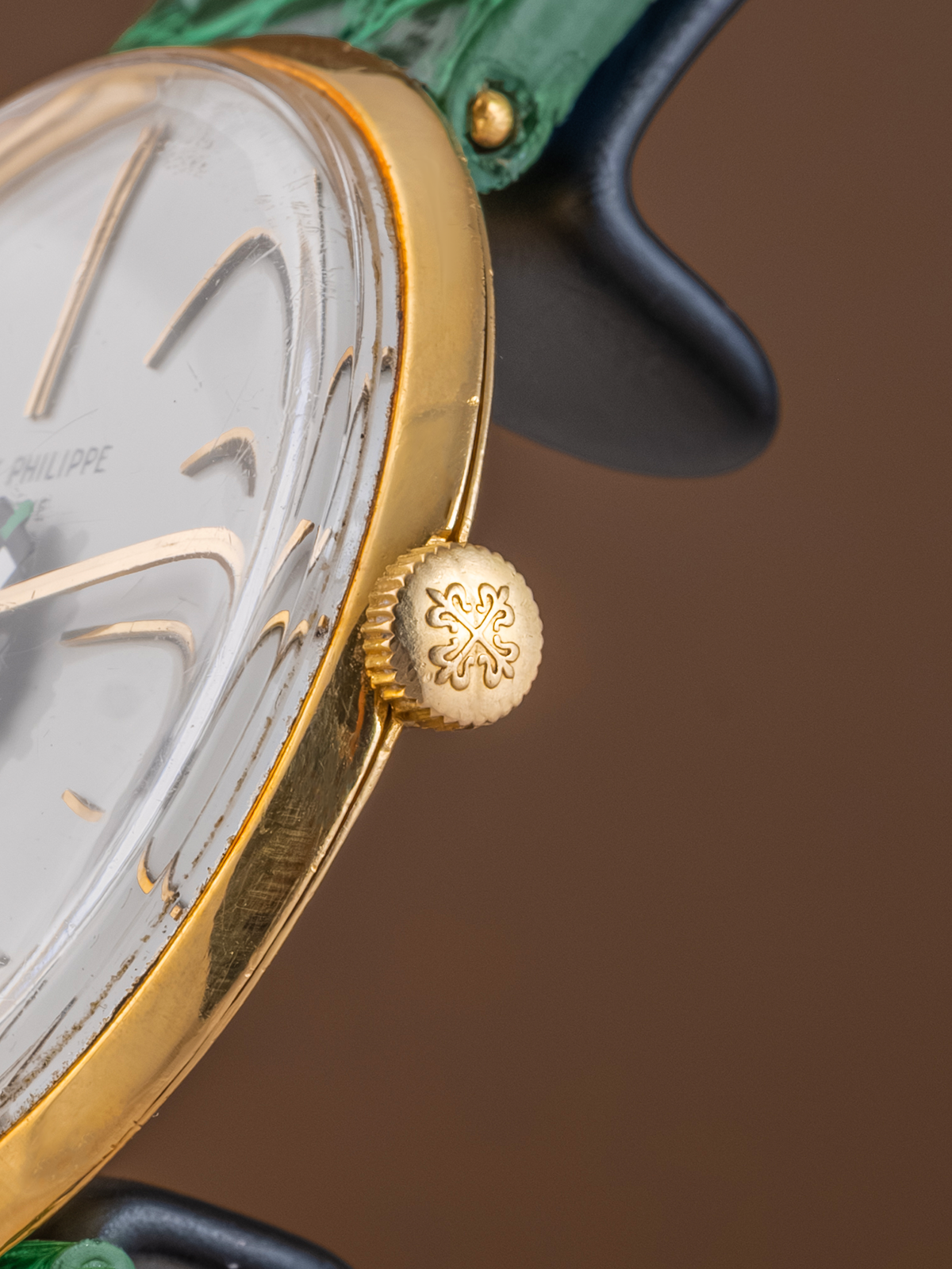 Close-up of a gold watch with a detailed face on a brown background