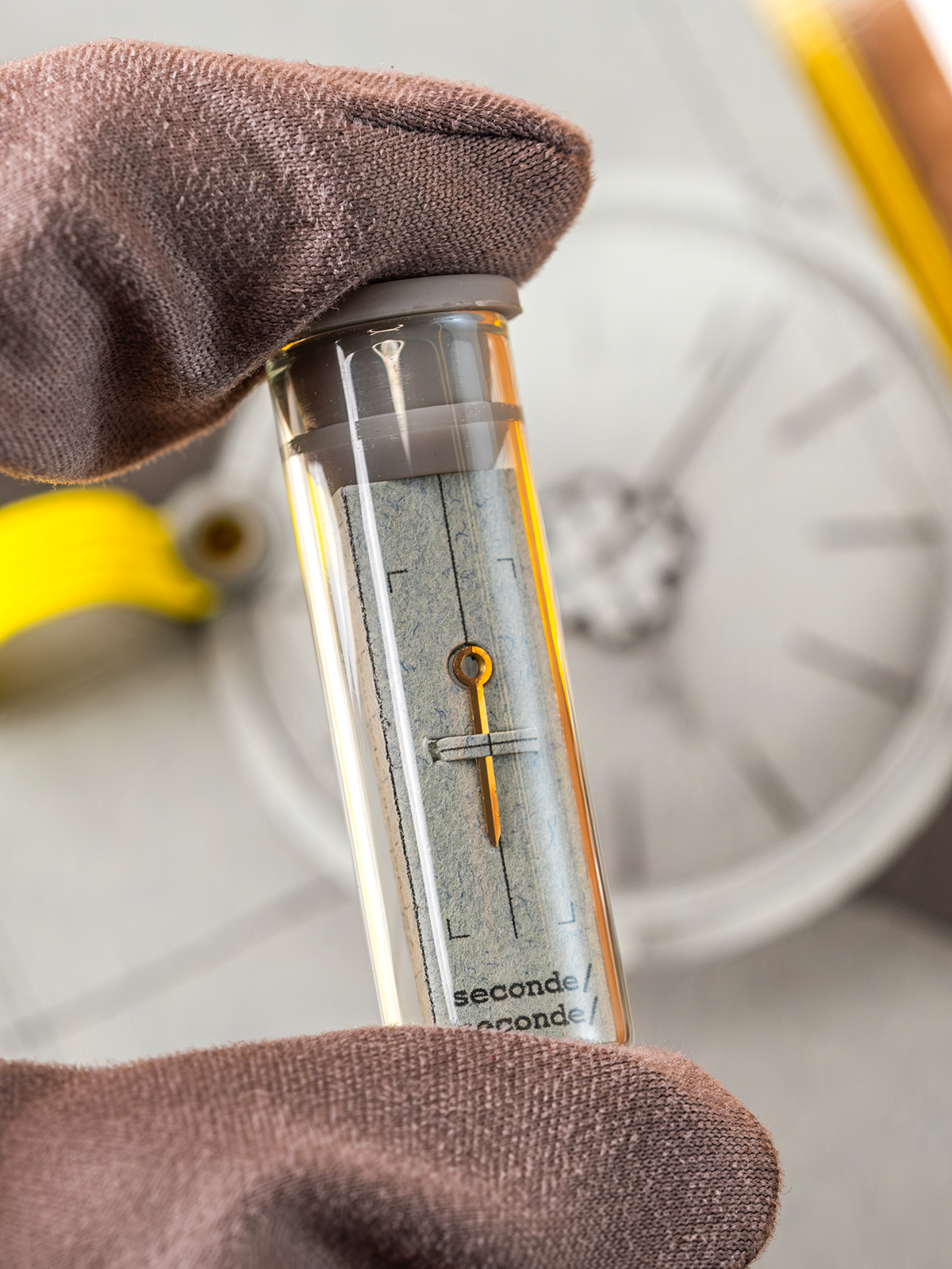 Close-up of a timepiece with a秒针 (second hand) held by a gloved hand, blurred background