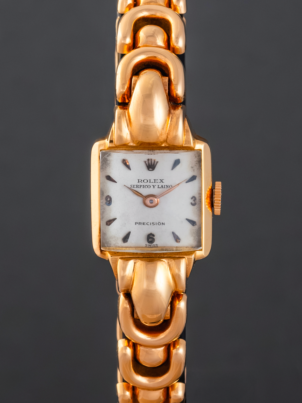 Gold wristwatch with a visible brand logo on a dark background