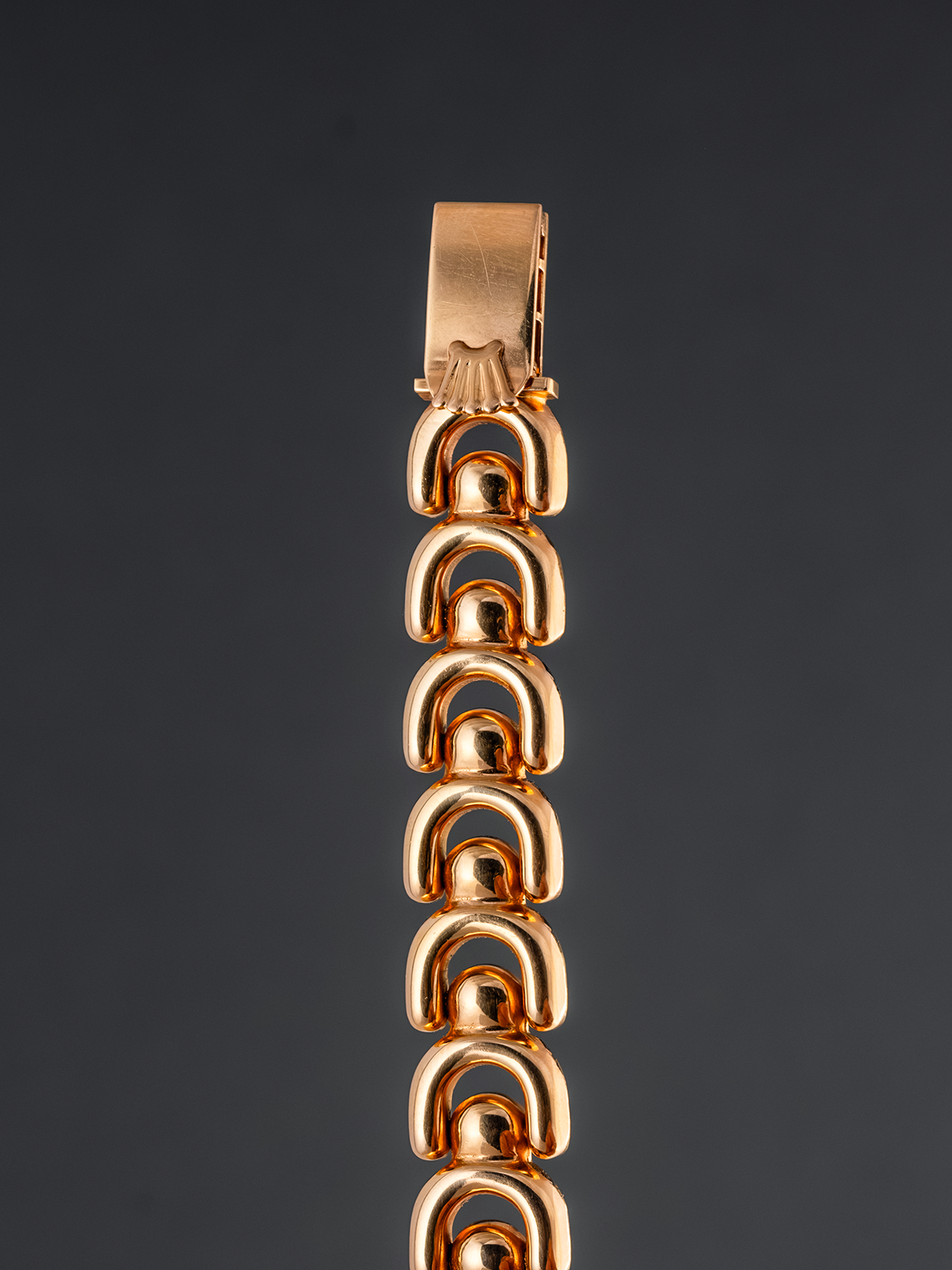 Gold bracelet on a reflective surface with a dark background