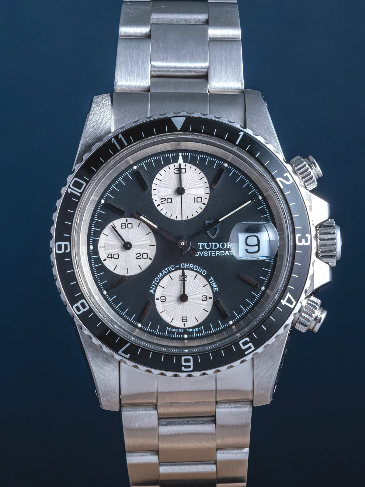 Silver Tudor watch with a dark face on a blue background