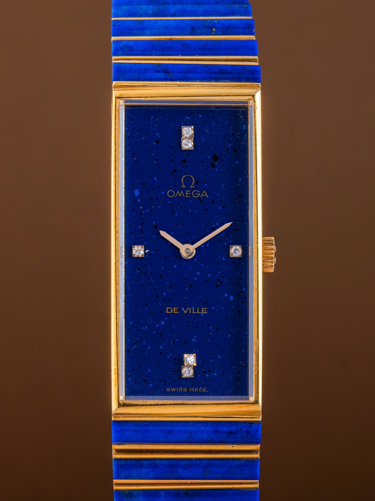 Luxury watch with blue face and gold accents on a brown background