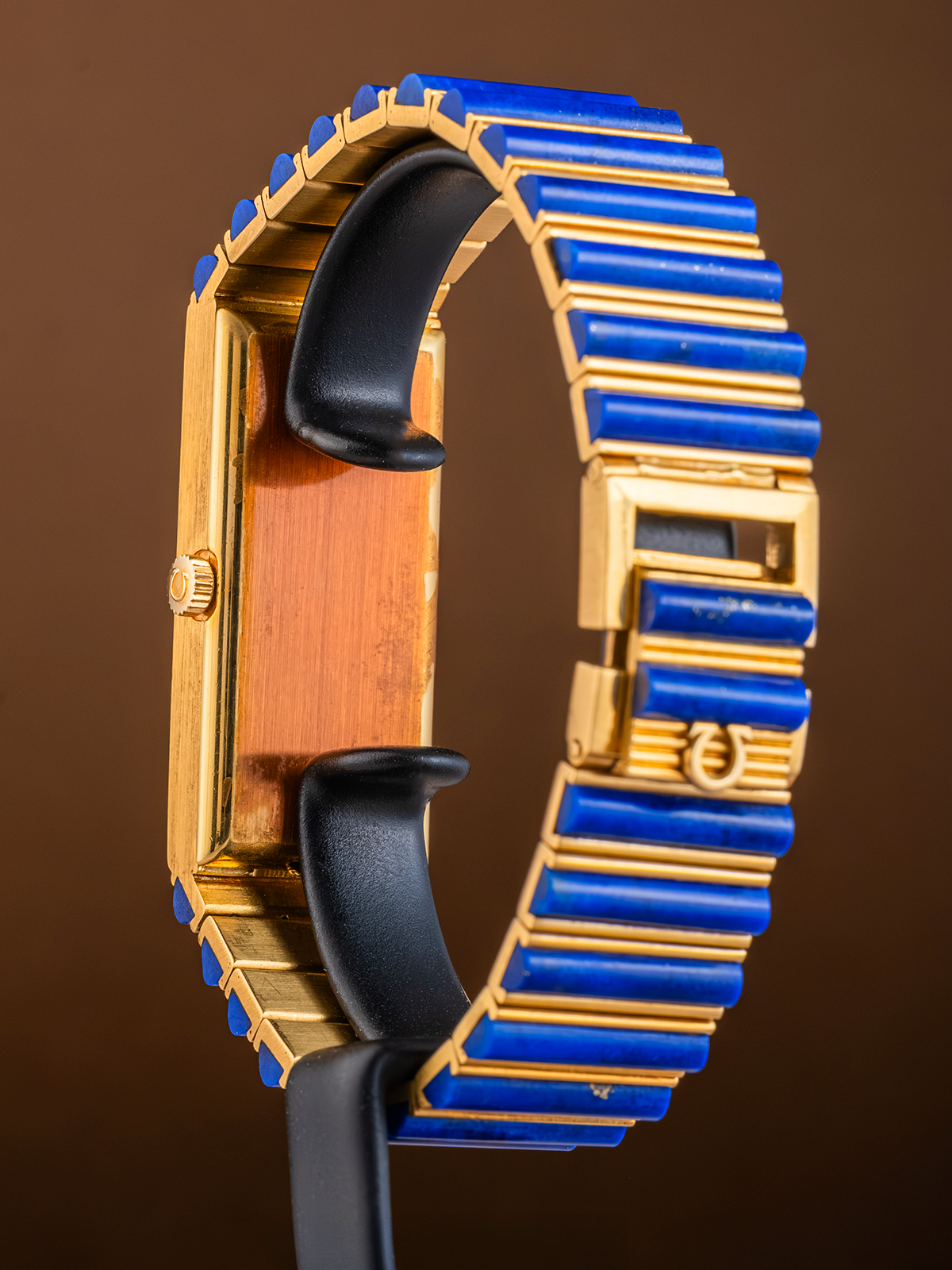 Luxury watch with gold and blue band on a brown background