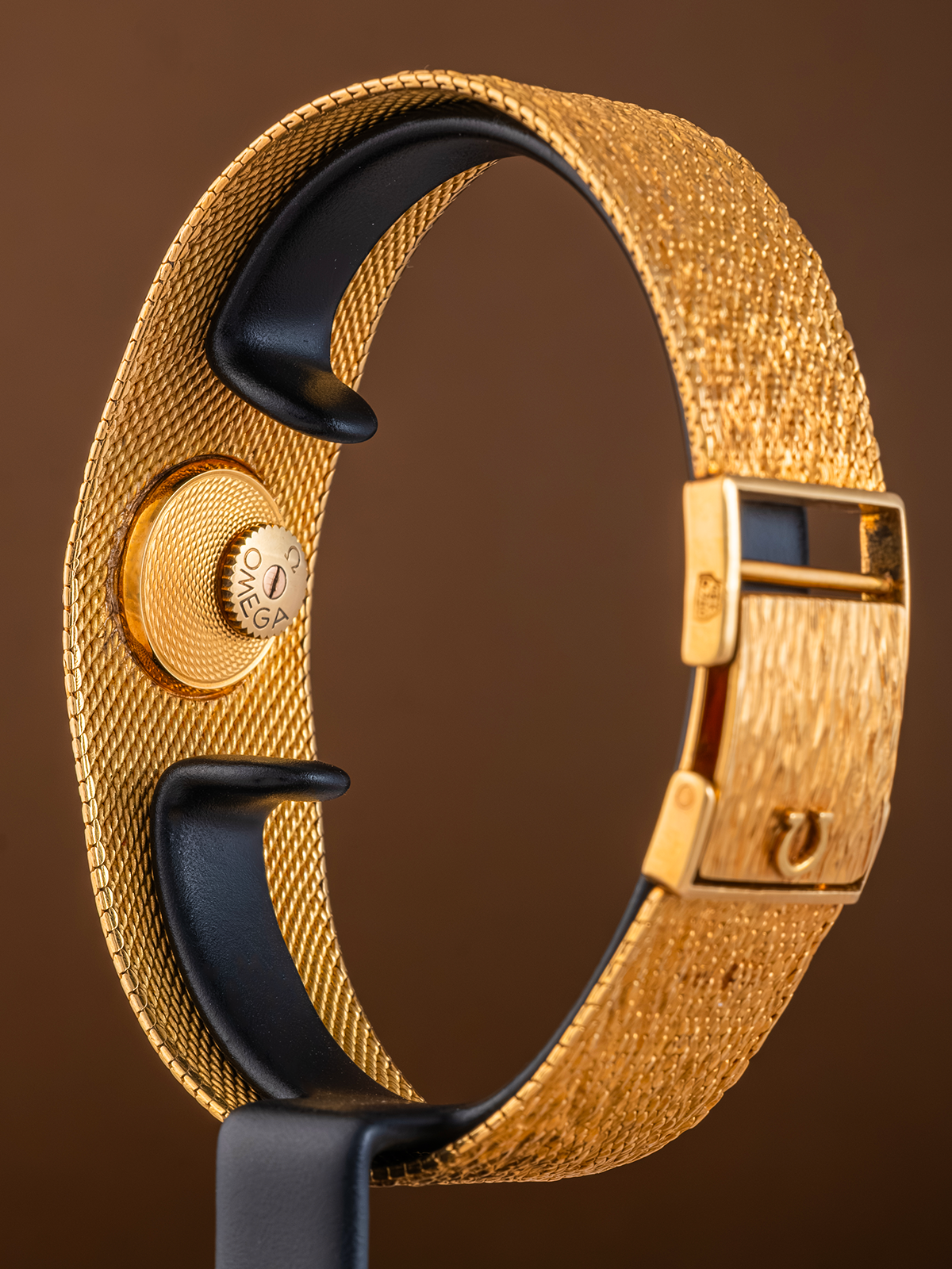 Gold bracelet with black accents on a brown background