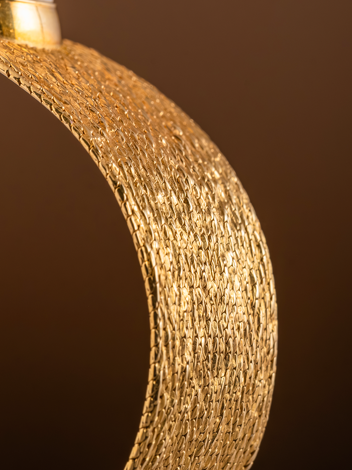 Close-up of a textured gold ring against a brown background