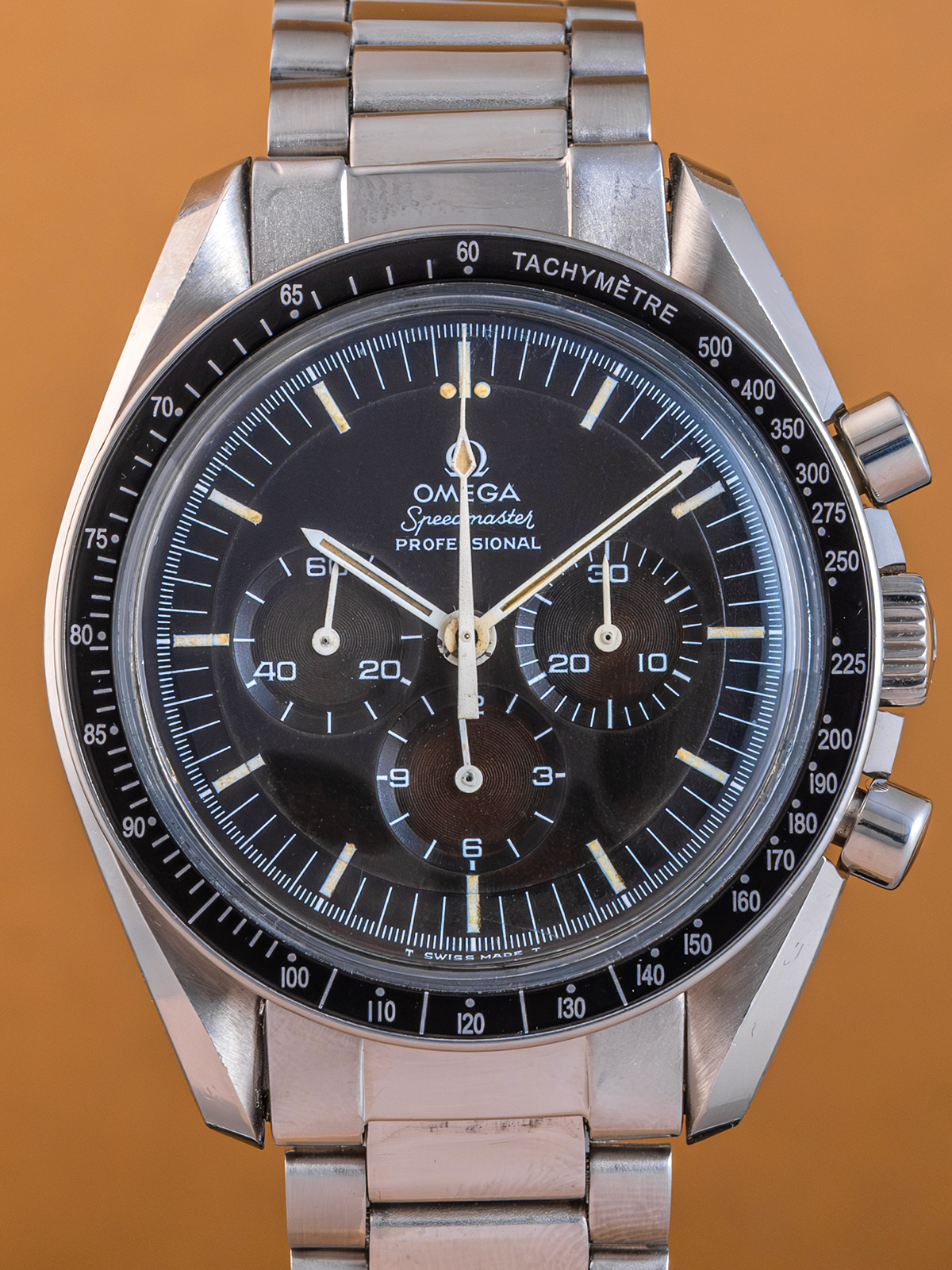 Silver Omega watch with black dial on a brown background