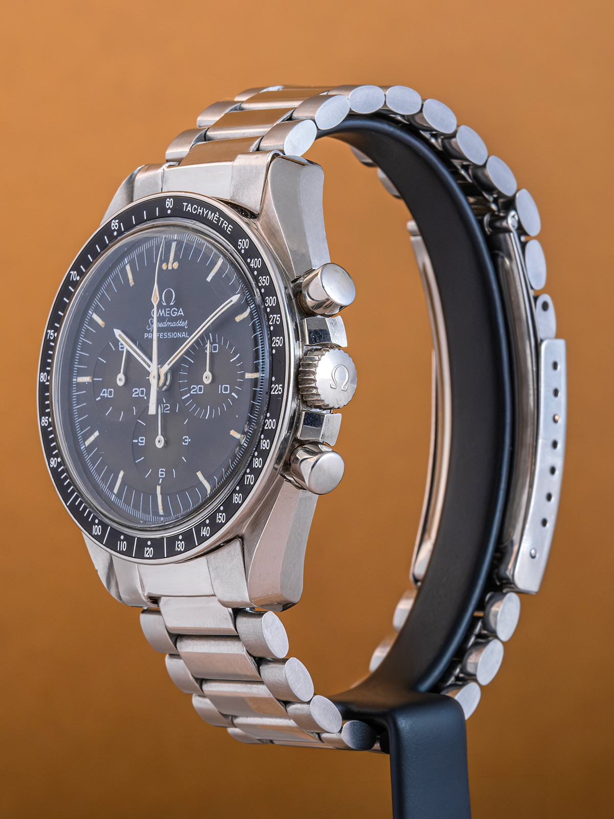 Silver watch with a black face on an orange background