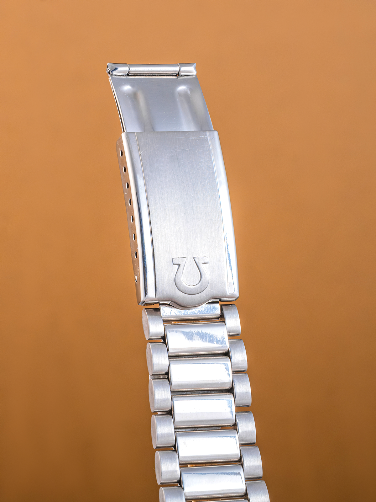 Silver watch band with clasp on a brown background