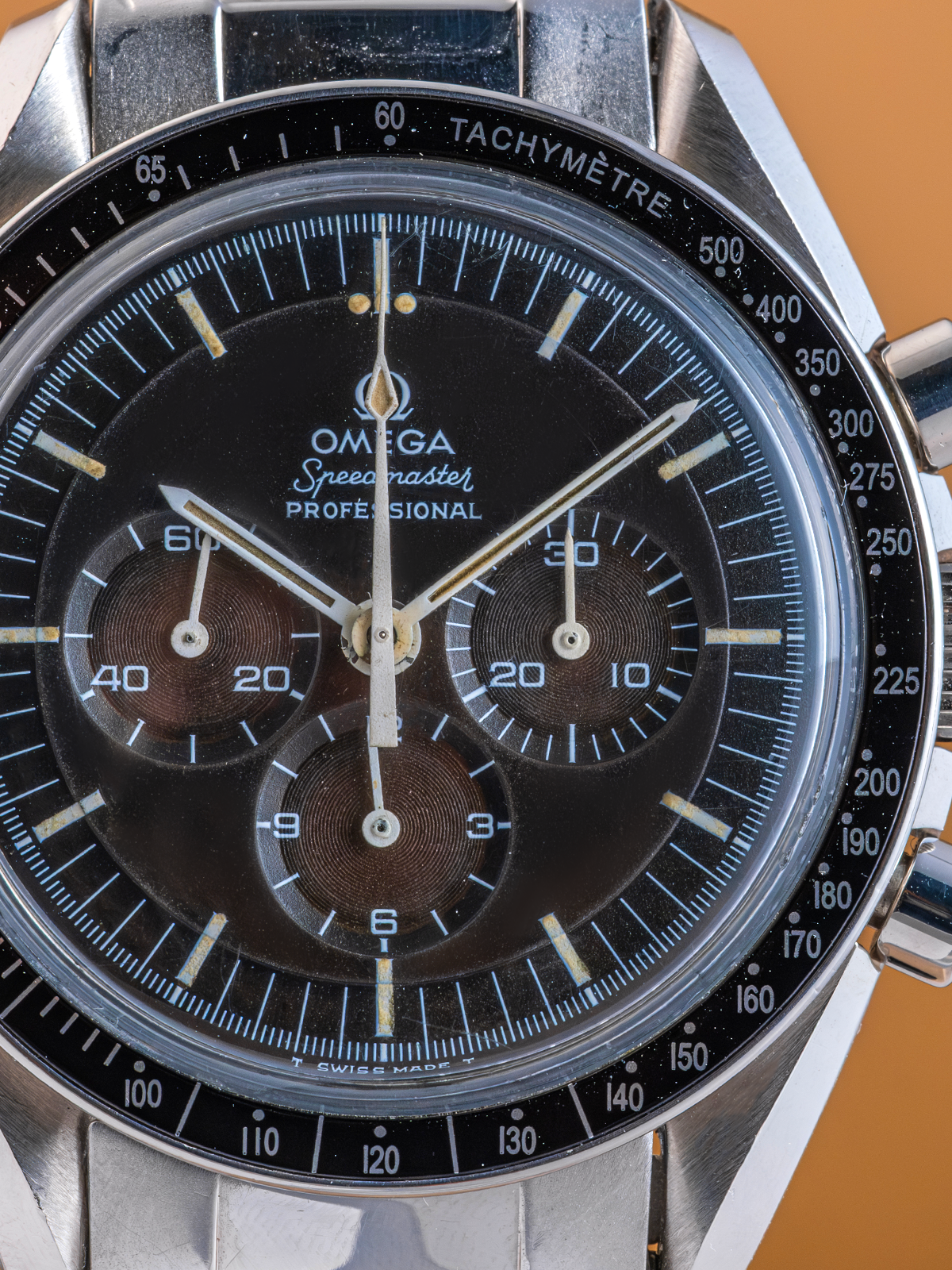 Close-up of a Omega Speedmaster Professional watch face on a brown background