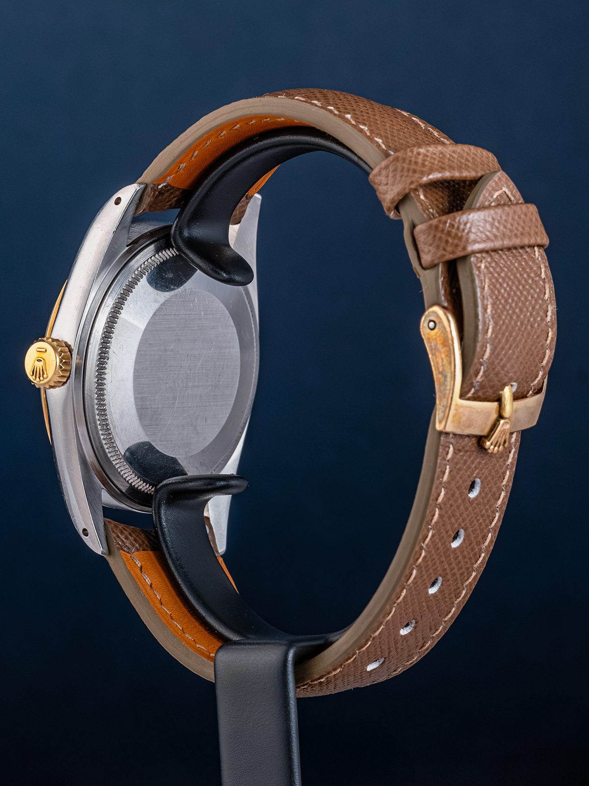 Watch with brown leather strap and gold accents on a dark blue background