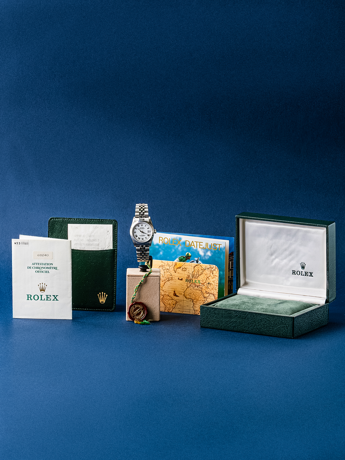Rolex watch with packaging and accessories on a blue background