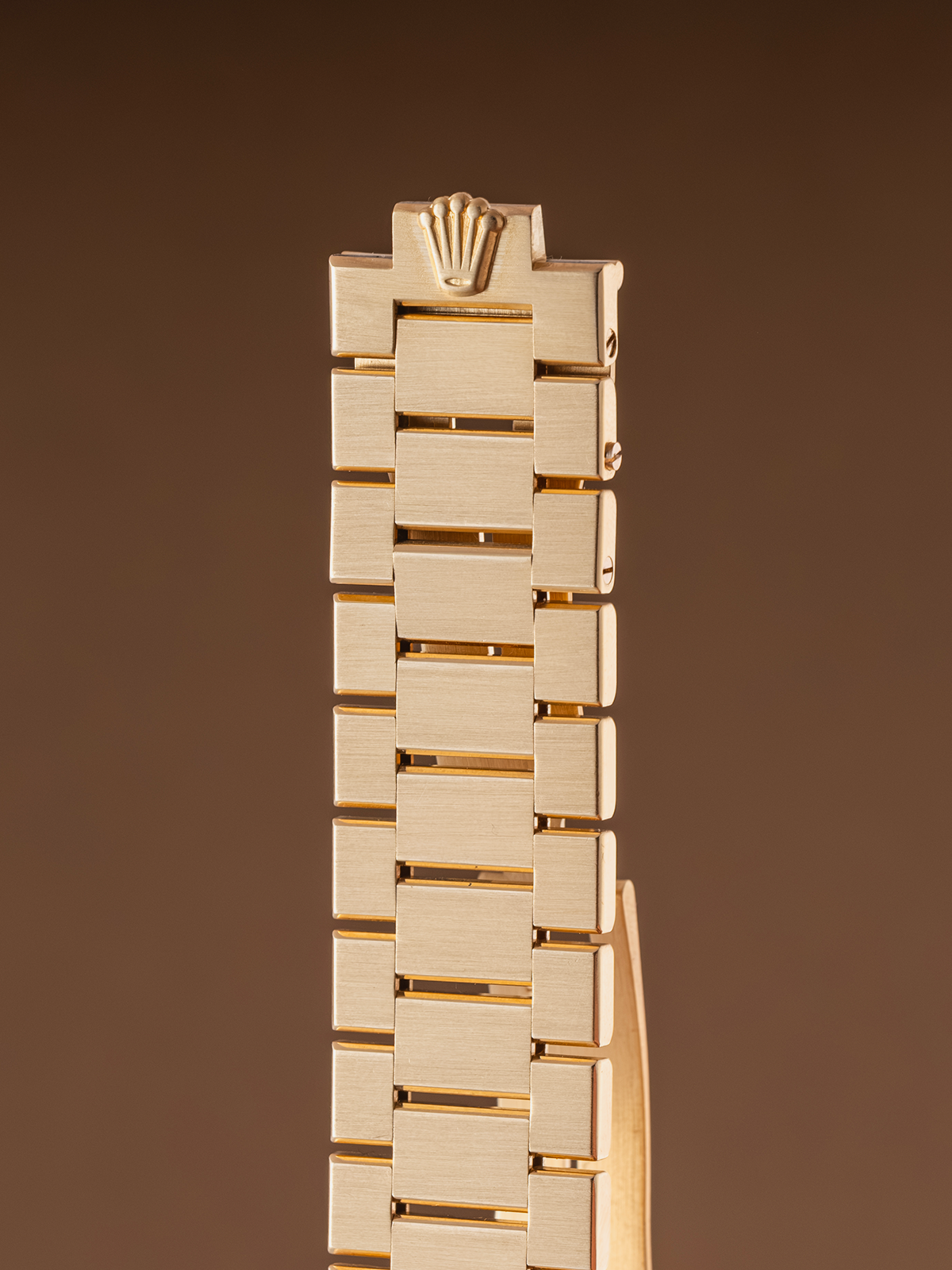 Gold watch strap on a brown background