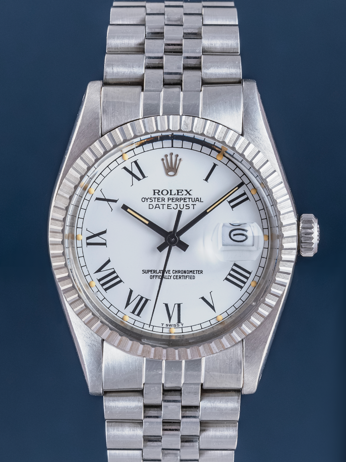 Silver Rolex watch with a white face and Roman numerals on a dark blue background