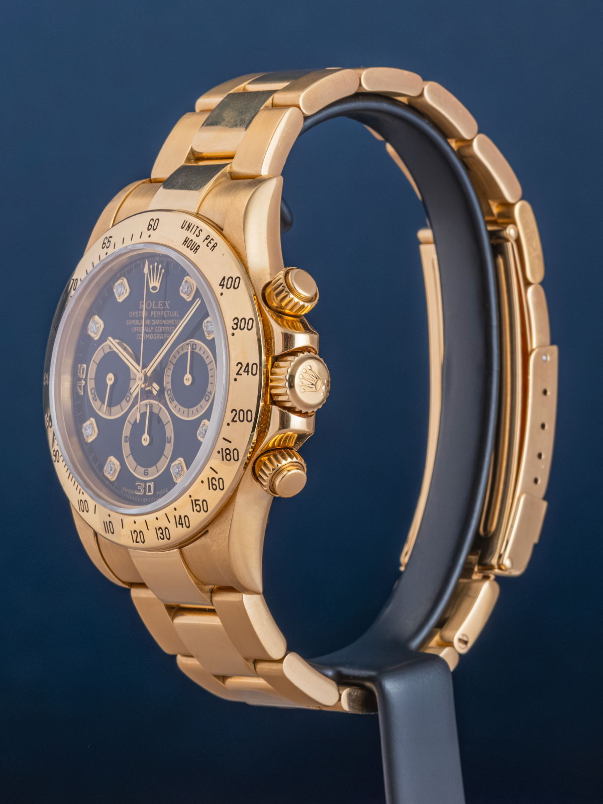 Gold watch with a blue face being examined by a magnifying glass on a dark background