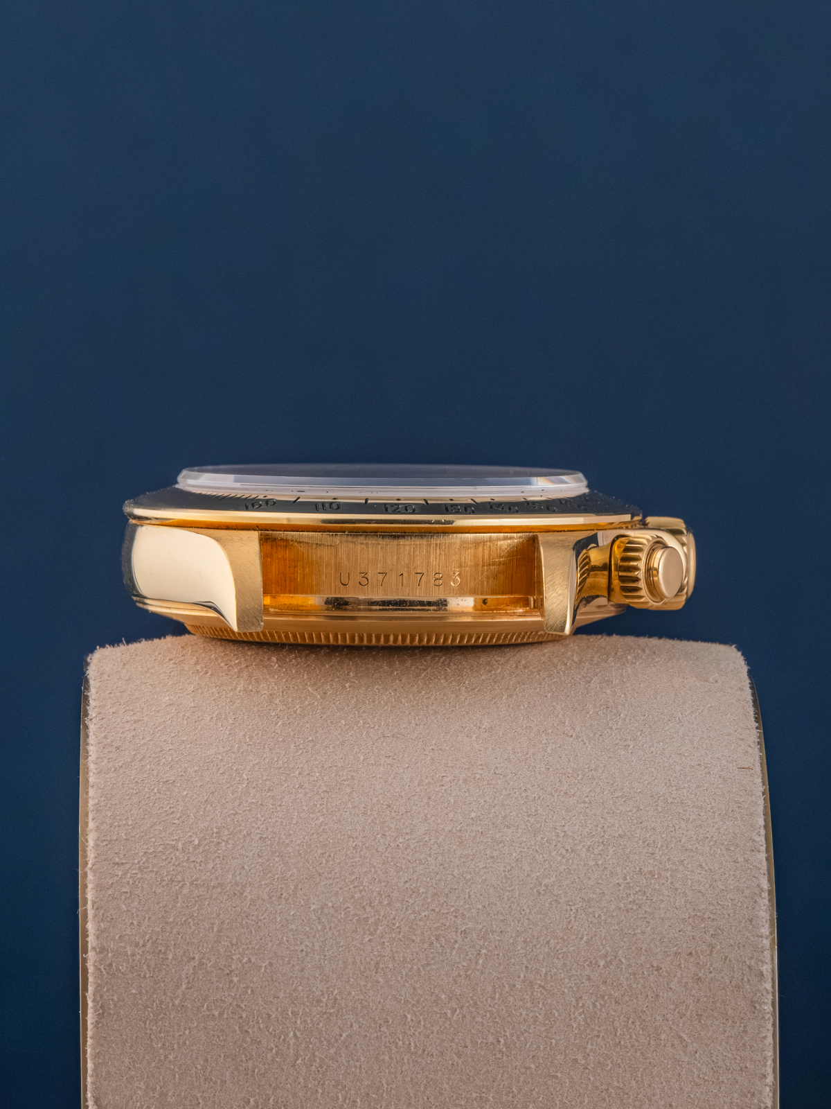 Gold watch on a gray cushion with a blue background