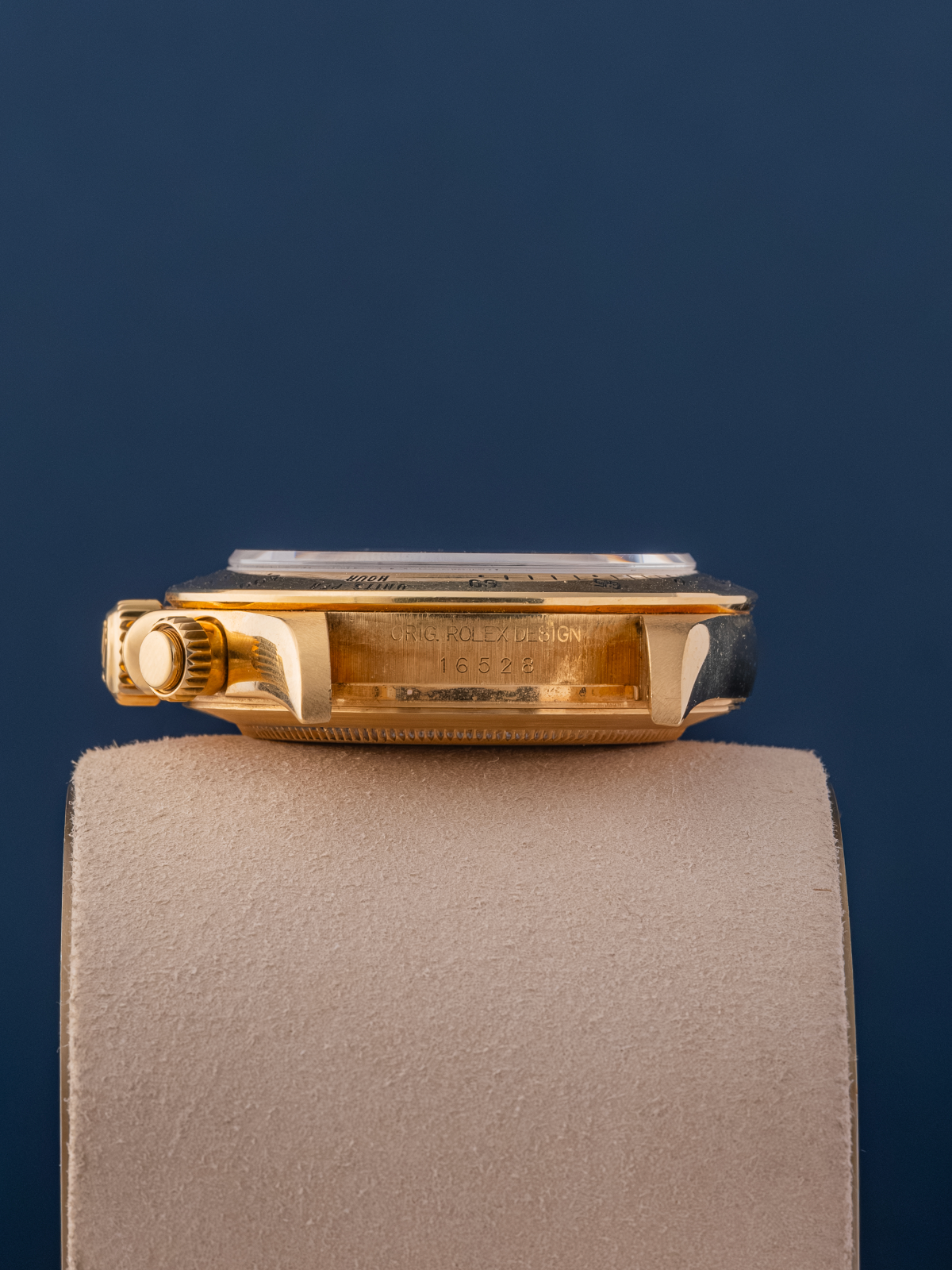 Gold watch on a gray stand with a dark blue background