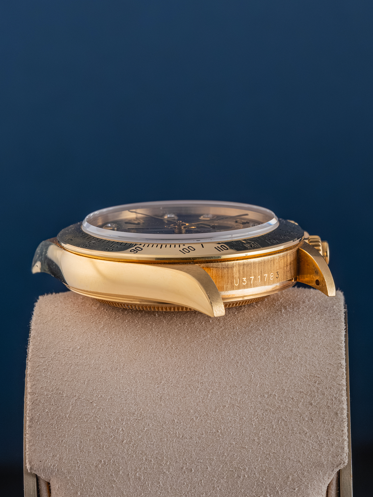 Gold wristwatch on a gray stand with a dark blue background