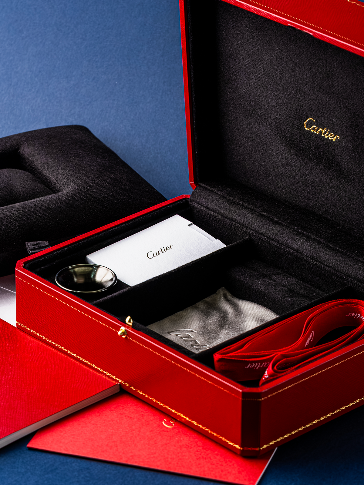 Cartier jewelry box with red interior and gold accents on a blue background