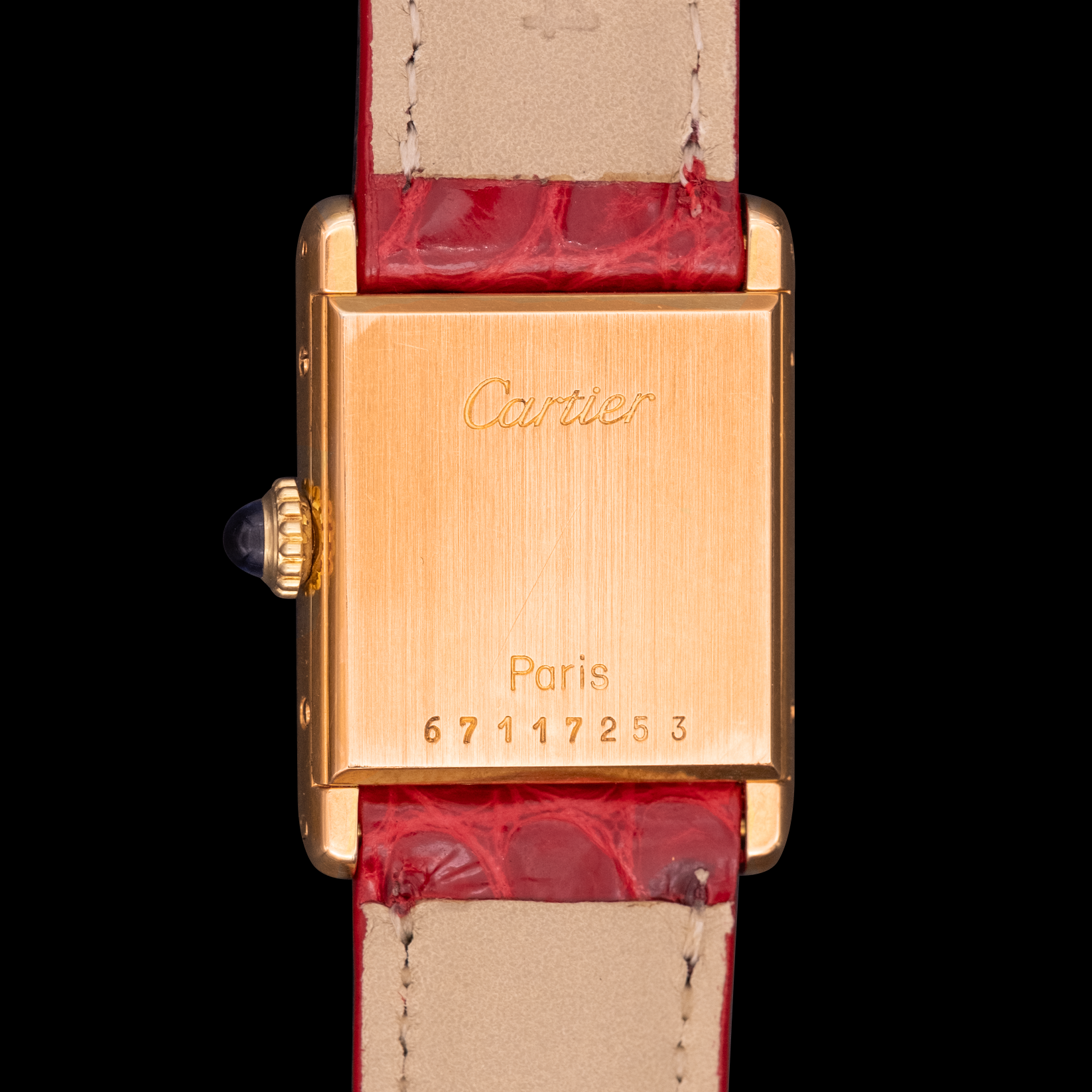Cartier watch with gold case and red leather strap on a black background